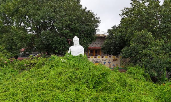 White meditation statue seated on a planted mound in the institute garden