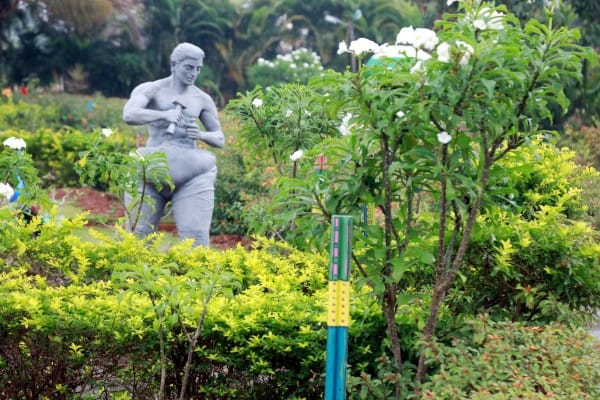Stone statue among flowering shrubs beside the garden walk